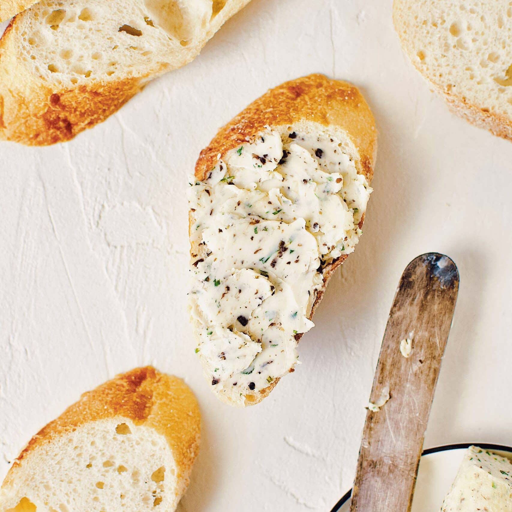 A single green leaf in a clear glass of water on white background.