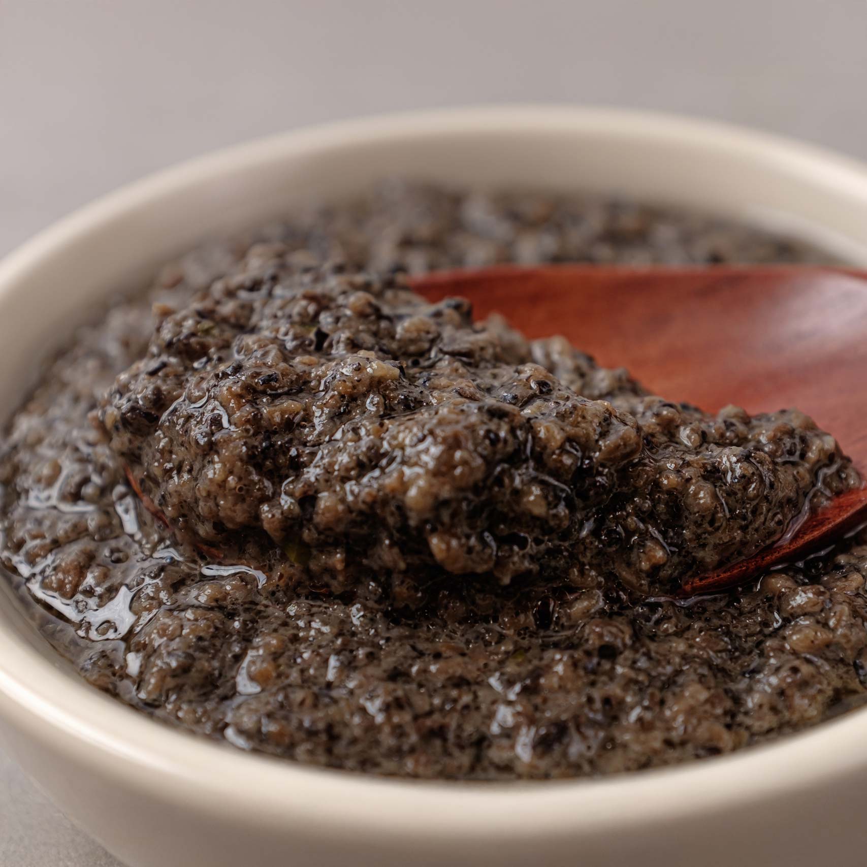 A single green leaf in a clear glass of water on white background.