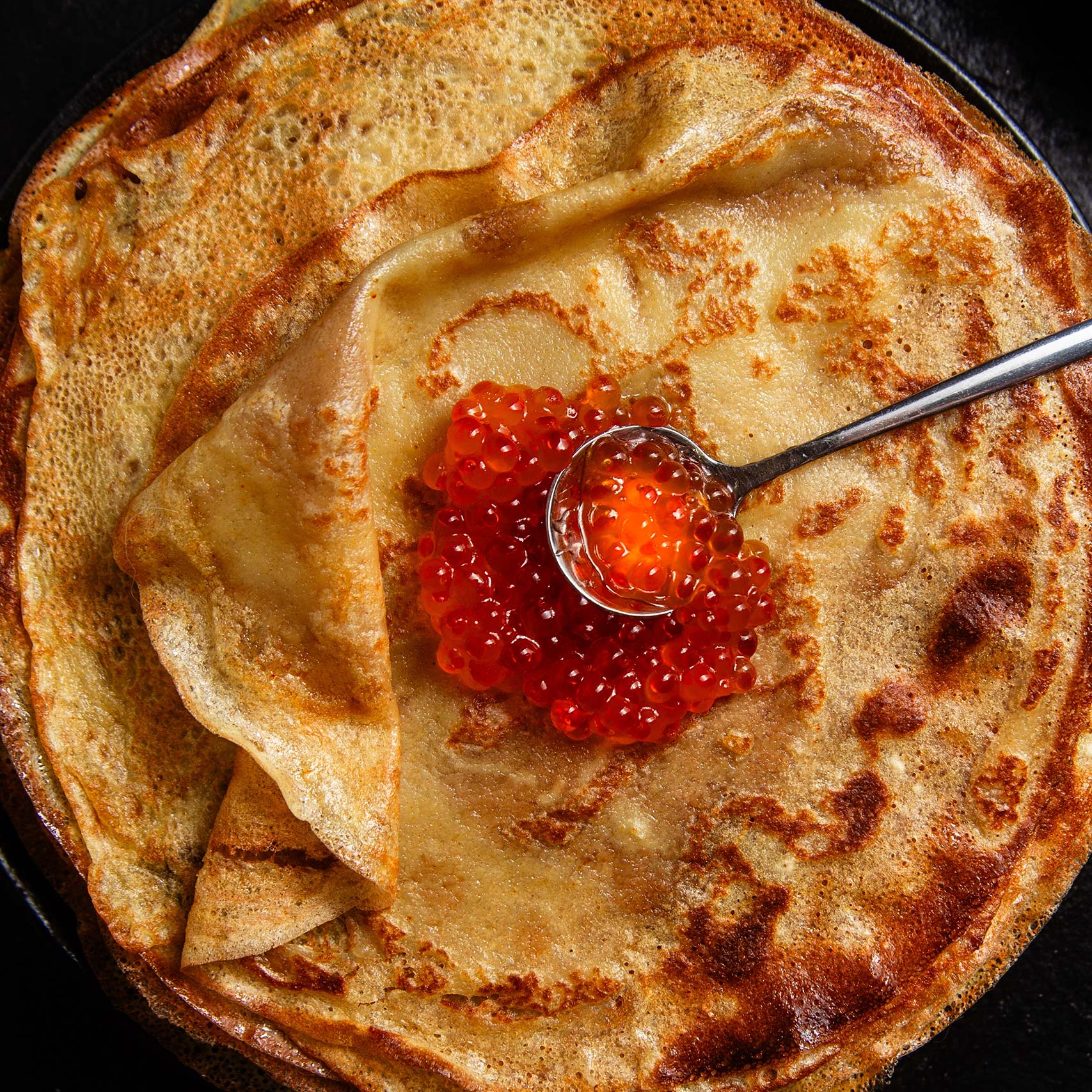A single green leaf in a clear glass of water on white background.