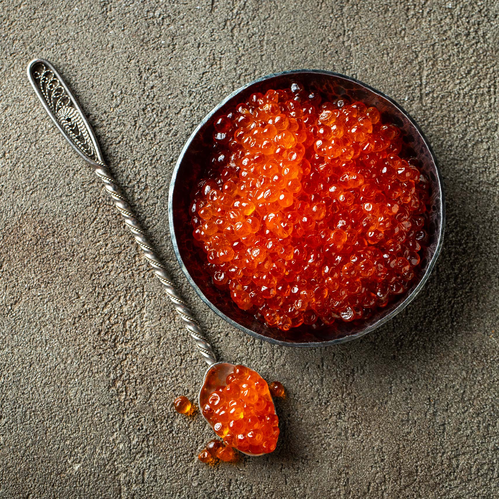 A single Monstera leaf in a clear glass vase against a white background.